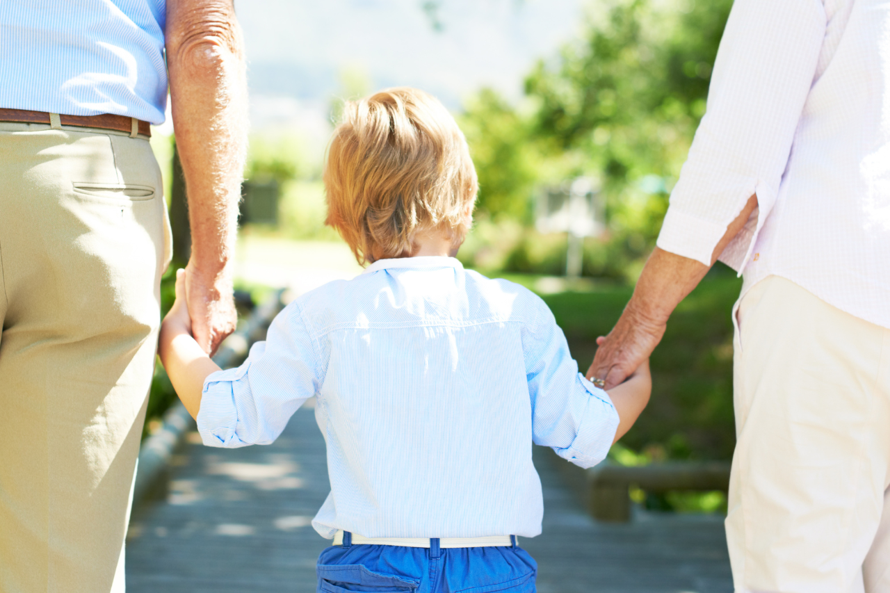 Elderly couple holding childs hand